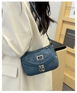Detail of blue faux leather crossbody bag with pleated texture and multi-zipper pockets