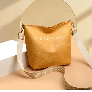 Détail d'un sac cabas jaune vif montrant la texture cuir et la bandoulière jacquard