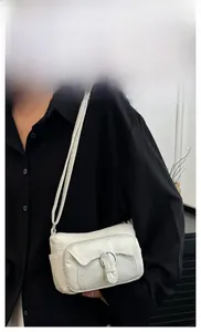 Side view of white faux leather crossbody bag with silver buckle and adjustable strap