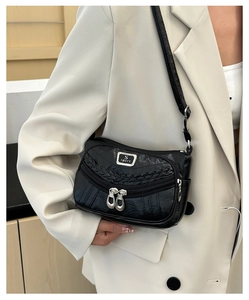 Detail of black faux leather crossbody bag with woven texture and double zipper pockets