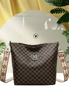 Détail du sac seau marron vintage avec motif M et bandoulière large de style ethnique