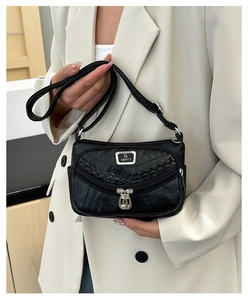 Detail of black faux leather crossbody bag with triple zippers and woven texture design