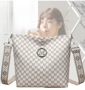 Détail d'un sac cabas en cuir souple avec imprimé monogramme et bandoulière en jacquard