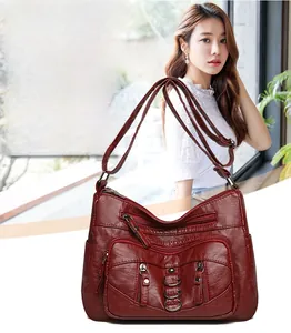 Detail view of burgundy multi-pocket crossbody bag with metallic rings and adjustable strap