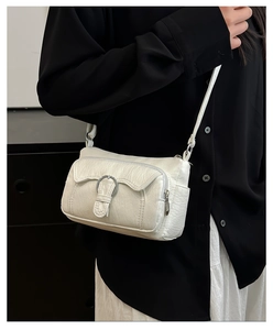 Detail of white pleated leather crossbody bag with silver ring buckle on front pocket