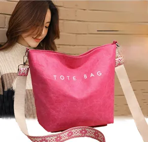 Détail du cabas rose vif avec lettrage blanc et bandoulière brodée style bohème
