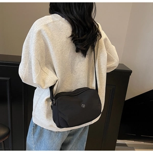 Close-up of a stylish black nylon dumpling bag worn by a model as a crossbody shoulder bag