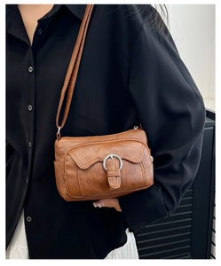 Brown vintage shoulder bag with textured faux leather and adjustable strap on a model