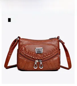 Detailed front view of brown lychee grain faux leather crossbody bag with multiple zippers