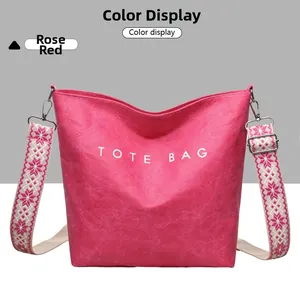 Gros plan du sac cabas rose rouge avec texture gaufrée et bandoulière à motif floral
