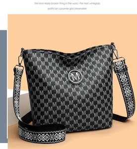 Détail du sac cabas noir avec monogramme M et bandoulière tissée aux motifs géométriques