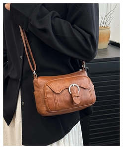 Brown litchi leather crossbody bag with front metal buckle pocket shown on a model