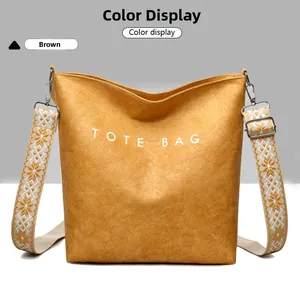 Détail d'un sac cabas marron avec lettrage blanc et une bandoulière à motif ethnique