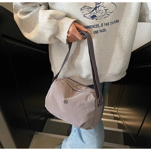 Detail of lavender nylon dumpling bag with adjustable wide strap shown on a model
