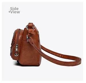 Side view of brown lychee grain leather crossbody bag showing multi-layer zipper pockets