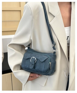 Detail of blue faux leather crossbody bag with metal buckle and decorative stitching