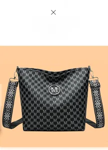 Détail du sac seau vintage noir avec imprimé M et bandoulière brodée géométrique