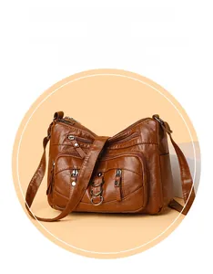 Detail view of dark brown faux leather crossbody bag with dual front zipper pockets