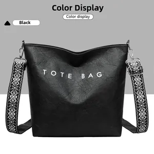 Détail du sac cabas noir avec lettrage blanc et large bandoulière à motifs géométriques