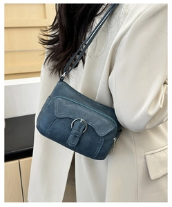 Detail of blue multi-pocket crossbody bag showing textured PU leather and zipper features