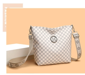 Détail d'un sac seau blanc avec motif M imprimé et une bandoulière tissée à motifs
