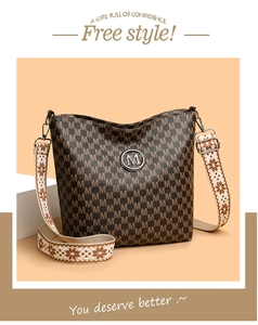 Détail du sac seau marron avec motif M et bandoulière tissée large de style ethnique