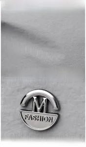 Détail du tissu en nylon gris et du logo rond en métal argenté poli avec gravure M