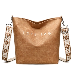 Détail du sac cabas marron texturé avec lettrage blanc et bretelles jacquard à motifs