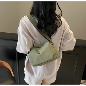 Close-up of a nylon dumpling bag in grey-green with a wide strap on model back