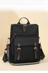 Dettaglio dello zaino in nylon nero con cinturini in pelle marrone e fibbia oro