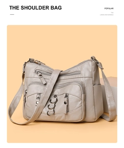 Detail view of large capacity crossbody bag with multiple zippers and metal ring accents