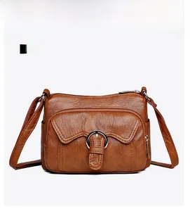Detailed front view of dark brown litchi textured leather crossbody bag with metal ring