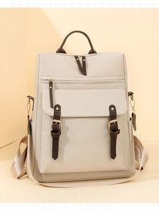 Dettaglio del tessuto beige impermeabile con manico in pelle marrone e fibbie in metallo dorato