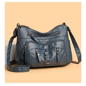 Detail of dark teal crossbody bag showing multi-compartment zippers and washed leather texture