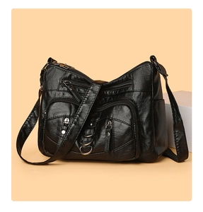 Detailed macro view of black soft leather crossbody bag with multiple metal zippers
