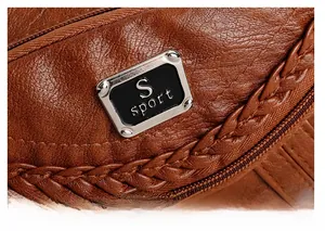 Detailed macro view of brown pebbled leather texture with S sport metal logo plaque