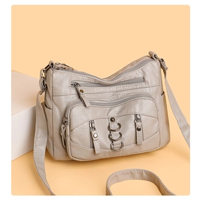 Detail view of multi-pocket crossbody bag with zipper compartments and metal rings