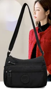 Detail of waterproof black nylon crossbody bag with three zipper compartments on a model