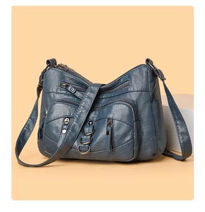 Detail of dark blue soft PU leather crossbody bag featuring multiple functional zippers