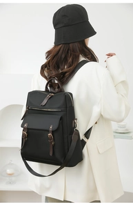 Vista posteriore di una donna con zaino chic in nylon nero e dettagli in pelle marrone