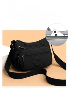 Detail view of water-resistant black nylon crossbody bag with multiple zipper compartments