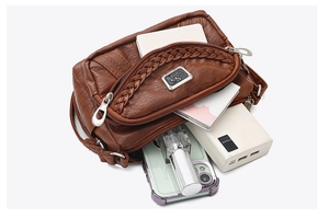 Detail view of multi-compartment soft leather crossbody bag with woven texture and pockets