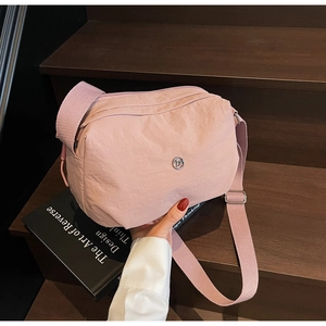 Detailed macro view of pink nylon dumpling bag on wooden steps with wide strap