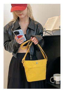 Yellow nylon bucket bag shown on a model in a black outfit for vibrant style contrast