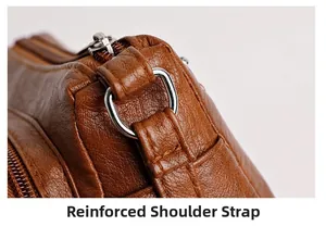 Detail showing reinforced shoulder strap stitching and silver D-ring on brown leather bag