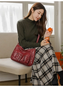 Detail view of burgundy multi-pocket crossbody bag with metallic rings and soft leather