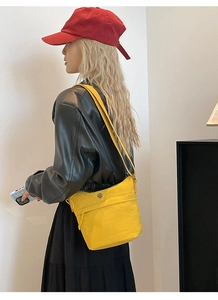 Detail of bright yellow nylon crossbody bucket bag with adjustable strap and metal buckle
