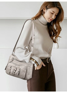 Detailed side view of multi-compartment crossbody bag in beige PU leather worn by model