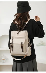 Dettaglio dello zaino beige per laptop con cinturini in pelle marrone e fibbie vintage