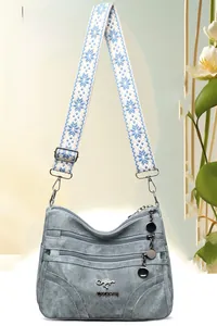 Close-up of a blue crossbody bag with multi-layer zippers and woven ethnic style strap
